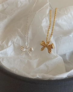 Elegant 925 sterling silver bow pendant necklace in gold and silver finish on white paper