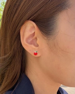 Detailed close-up of cute red apple stud earring with green leaf on a model ear