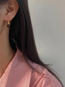 Elegant gold hook earrings featuring brown tiger eye stone spheres on model's ear