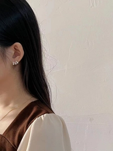 Close-up of elegant gold stud earrings featuring three natural pearls in a neat row