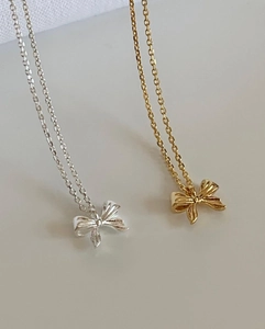 Macro shot of gold and silver bow pendants with fine O-chain jewelry details