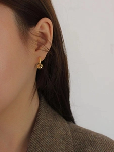 Detail of minimalist gold disc drop earrings worn by a model in elegant style