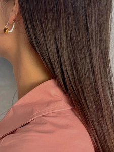 Close-up of tiger eye stone earring with silver hook on a model with long hair