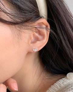 Elegant S925 sterling silver bow earrings with zircon and pearl on a model's ear