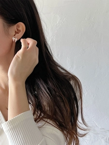 Close-up of elegant white bow-shaped earrings worn by a model in natural light