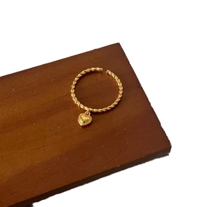 Elegant gold twisted rope open ring with a dangling heart pendant on a wooden surface