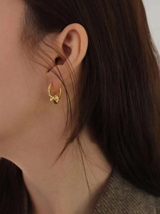 Detailed view of model wearing a knot design gold-plated S925 silver hoop earring