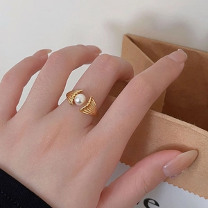 Detail of adjustable gold ring with white pearl and shell design on model hand