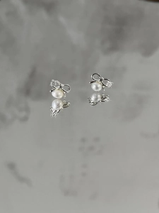 Close-up of S925 sterling silver bow earrings with zircon and dangling white pearls