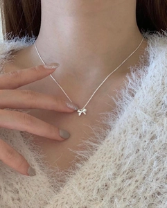 Elegant 925 sterling silver bow pendant necklace worn by a model on a white sweater