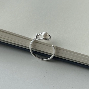 Minimalist S925 sterling silver open ring with a round white pearl on textured paper