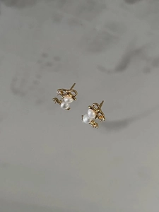 Detail of S925 silver gold bow earrings with micro-inlaid zircons and twin white pearls