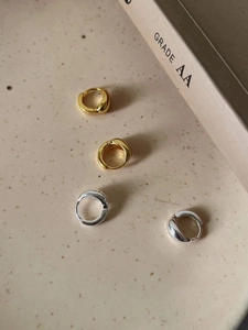 Makroaufnahme polierter unregelmäßiger Creolen aus 925er Sterlingsilber in Gold und Silber