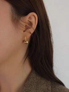 Detail of minimalist gold-plated S925 sterling silver earring with spherical charm on model
