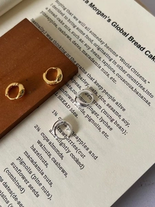 Minimalistische Creolen aus 925er Sterlingsilber in Gold und Silber auf einem Buch