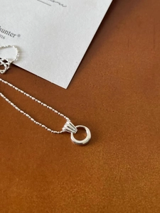 Close-up of S925 sterling silver ring pendant with delicate bead chain on brown leather