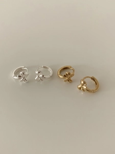 Detail view of gold and silver bow-shaped hoop earrings with polished finish