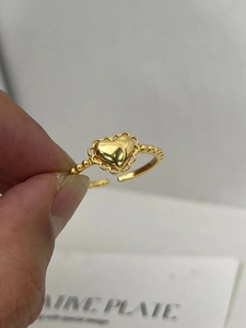 Macro detail of gold-plated s925 silver heart ring with lace edge and beaded band