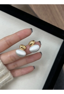Detail of two-tone gold and silver oval earrings showing brushed metal texture