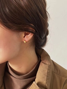 Nahaufnahme eines Models mit minimalistischen polierten Gold-Creolen im Tropfen-Design