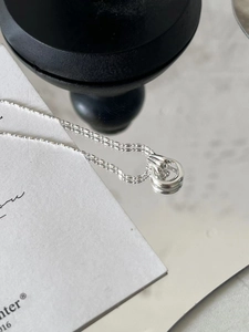 Macro shot of S925 sterling silver ball chain necklace with interlocking ring pendant