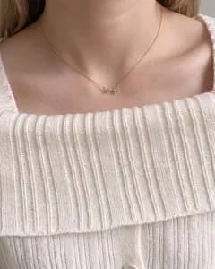 Collier fleurs minimaliste en argent S925 doré porté sur un gilet blanc