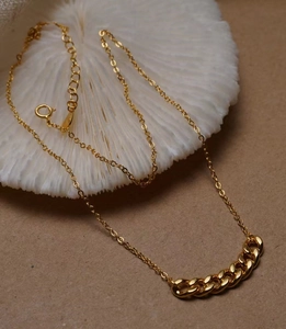 Dettaglio di una collana a catena groumette dorata su decoro di corallo bianco