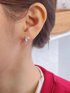 Gros plan d'une boucle d'oreille cœur en argent 925 et zircon portée sur une femme