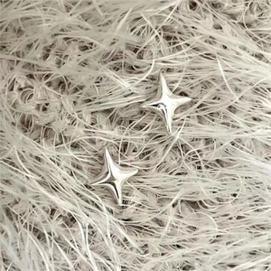 Minimalist 925 sterling silver star-shaped stud earrings on soft plush background