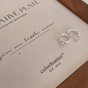 Macro shot of 925 sterling silver hoop earrings with delicate cross charms on display