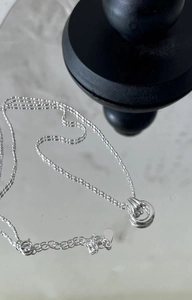 Detail of S925 sterling silver peace buckle necklace with intertwined rings on mirror surface