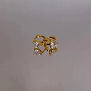Gros plan de boucles d'oreilles cœur dorées avec zircon clair et reflet de miroir chic