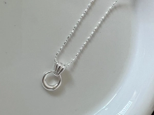 Macro shot of minimalist S925 sterling silver ring pendant with polished ball chain detail