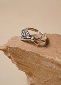 Detailed view of 925 sterling silver bow ring on natural stone with adjustable open band