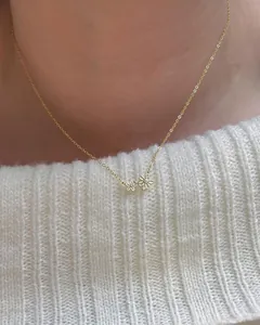 Gros plan d'un collier en argent S925 doré avec deux petites fleurs et pierres fines