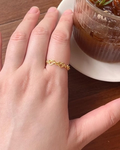 Gros plan détaillé de la bague en forme de cœur en or 18 carats portée sur le doigt