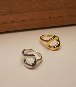 Detailed view of silver and gold irregular twisted open rings on a wooden stand