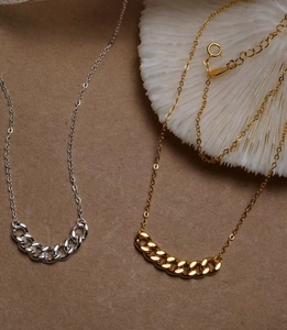 Dettaglio di collane a catena color argento e oro con chiusure regolabili su pelle