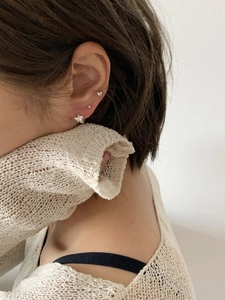 Close-up of 925 sterling silver floral and heart stud earrings worn by a model