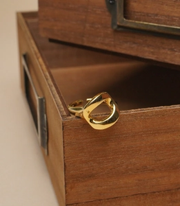 Close-up of golden hollow geometric ring with polished finish on a wooden box