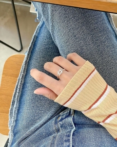 Close-up of a twisted silver knot open ring worn on a finger with denim background