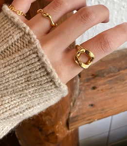 Detailed view of layered gold irregular geometric rings styled on a model finger