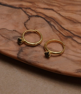 Detail of 925 sterling silver gold-plated hoop earrings with six-claw black stone