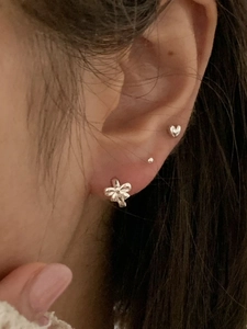 Detail of 925 sterling silver bow and heart stud earrings worn by a female model