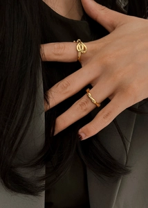Detail of high-polish gold twist knot and bamboo joint rings on model's fingers