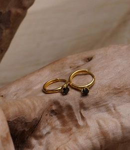 Detailed view of gold earrings with black round cubic zirconia in a six-prong setting