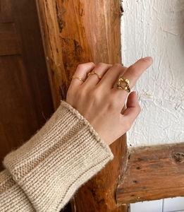 Detailed view of three gold-plated minimalist rings on hand in warm natural lighting