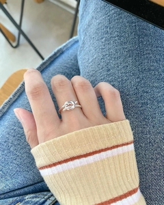 Close-up of minimalist silver twisted knot ring worn against denim and striped sweater