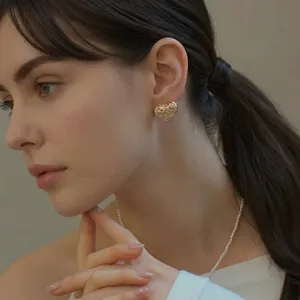 Golden heart-shaped woven studs with a matching pearl necklace on a female model