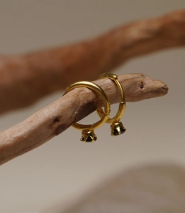 Detail of vintage gold hoops with black gemstone drops hanging on a rustic wooden branch